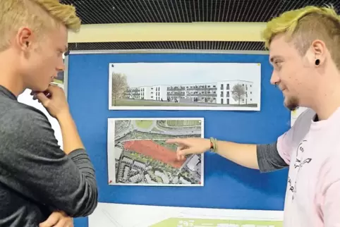Joel Hankiewicz und Daniel Seidler von der Engagierten Jugend Neustadt schauen sich die Pläne für den Wohnkomplex an.