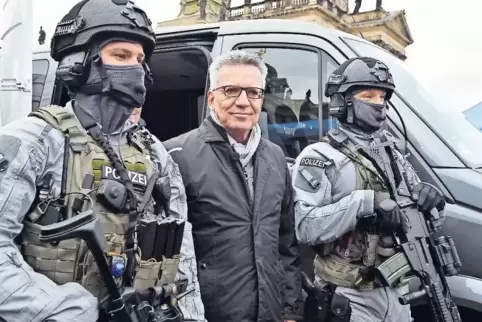„Behörden greifen heute teilweise schneller zu“: Bundesinnenminister Thomas de Maizière – hier mit zwei schwer bewaffneten Männe