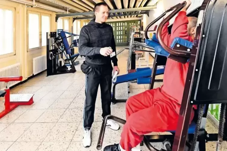 Kann von Sport nicht genug bekommen: Björn Römer beim Training mit einem Gefangenen an Geräten im Kraftraum.