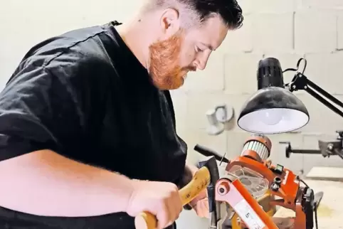 Mag es gern scharf: An einer Bandschleifmaschine verpasst Tobias Ruth einem stumpfen Beil zunächst einen Vorschliff.