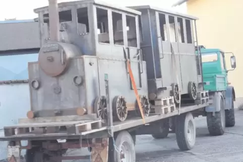 Zwei Waggons (nebeneinander platziert) und eine Lok machen sich gut verzurrt auf die Reise.