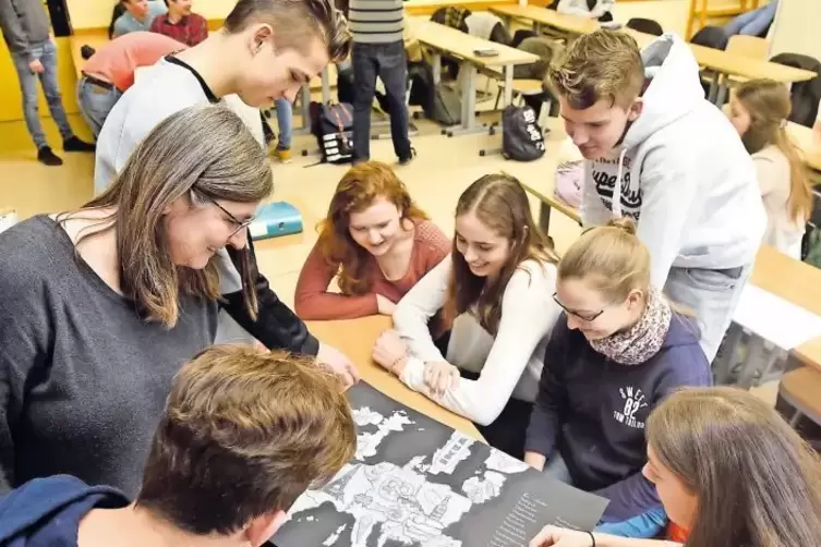 So macht die EU-Darstellung Spaß: Lehrerin Silvia Hauser (links) und Schüler mustern amüsiert eine Länderkarte, die Typisches fü