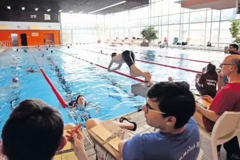 Die Helfer des Schwimmclubs haken am Beckenrand die Bahnen ab.