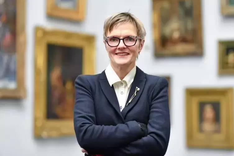 Die Direktorin der Mannheimer Kunsthalle, Ulrike Lorenz, steht in der Kunsthalle vor einer Wand mit Gemälden. Foto: DPA