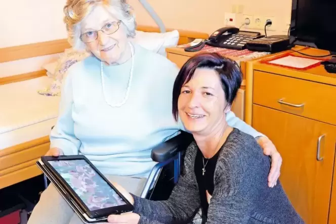 Mit Hilfe des Tablet-Computers kann Altenpflegerin Bianca Andrie-Wachter (rechts) Bilder zeigen, Musik vorspielen, Erinnerungen