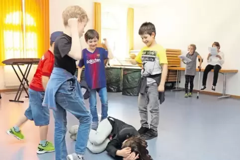 Szene aus der Probe, auf dem Boden: Olivia als Bartimäus, der von den Spielkameraden geschlagen und getreten wird.