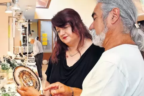 Turan Zunnun aus Teneriffa zeigt Martina Melcher Achatscheiben aus Brasilien, die er mit Acrylfarbe handbemalt hat.