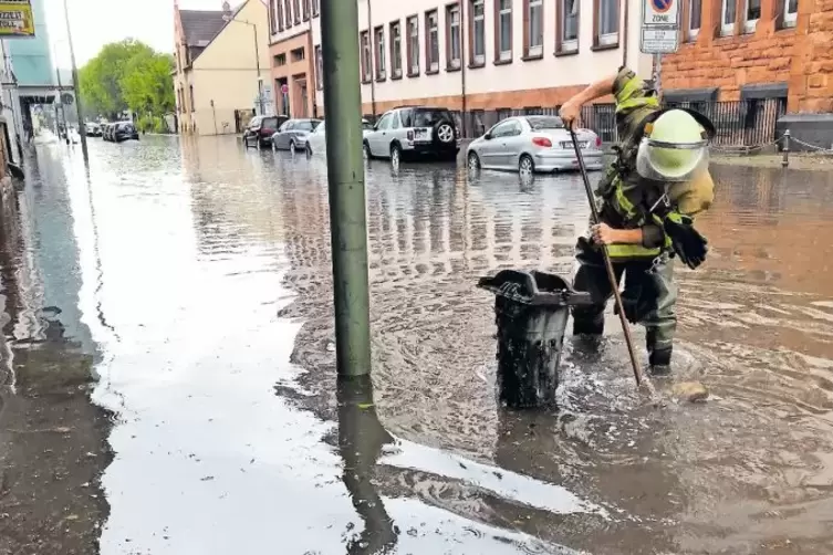 Ein Feuerwehrmann öffnet einen Gully in der Burgstraße, damit das Wasser besser abfließen kann.
