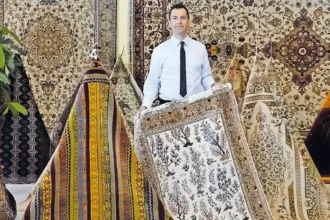 Amin Vafaei zeigt einen seidenen Ghom-Teppich.