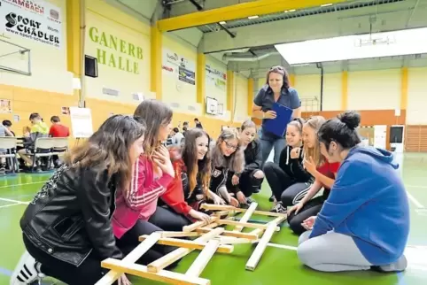 Nicht so leicht: Schülerinnen bauen aus Kanthölzern eine Brücke.