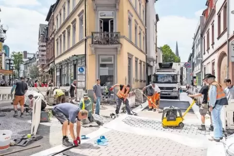 Bauarbeiter bringen am neuen barrierefreien Übergang von der Kerststraße in die Pirmasenser Straße einen Belag aus kunstharzgebu