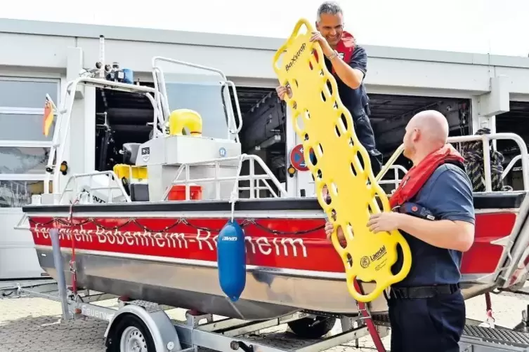 Michael Remmele und Daniel Bergmann (rechts) führen das neue Rettungsboot der Feuerwehr vor. Dazu gehört ein gelbes Spineboard, 