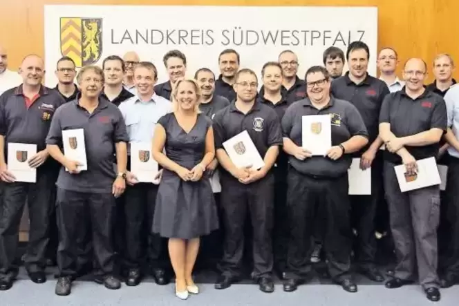 Landrätin Susanne Ganster stellt sich mit den neuen Ausbildern zum Gruppenfoto im Kreistagssaal.