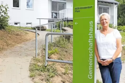 Irene Jennes, die Leiterin des SOS-Kinderdorfs Pfalz in Eisenberg, an einem der neuen grünen Hinweistafeln vor dem Dorfgemeinsch