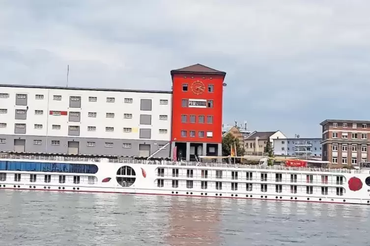 Flusskreuzfahrtschiffe liegen vor dem rotgestrichenen Mannheimer Schifffahrtspegel.