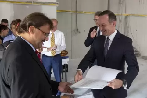 Wirtschaftsminister Volker Wissing übergibt in der neuen Halle den Förderbescheid an WCI-Geschäftsführer Rainer Trapp (links).  