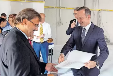 Wirtschaftsminister Volker Wissing übergibt in der neuen Halle den Förderbescheid an WCI-Geschäftsführer Rainer Trapp (links).