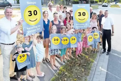 Stehen in der Iggelheimer Straße in Dudenhofen vor dem Parkplatz der Kindertagesstätte Naseweis und zeigen die Plakate, die Auto
