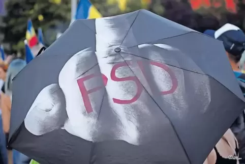 Eindeutige Botschaft: Ein Demonstrant in Bukarest zeigt mittels bedrucktem Regenschirm, was er von der PSD-Regierung hält.