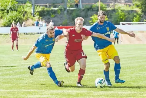 In die Mangel genommen: Felix Burkhard (Mitte) vom FC Queidersbach wird von Stefan Linck (l.) und Josef Wernz, FV Rockenhausen, 