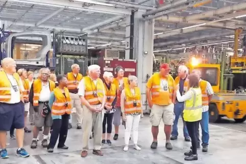 Die Tour führt die amerikanischen Gäste mitten durch die Produktionshalle. Immer wieder sausen Fahrzeuge vorbei.