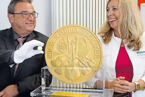 Volker Schleinkofer von der Sparda-Bank zeigt eine normale Münze neben der Riesenmünze, rechts seine Kollegin Stefanie Metzger.