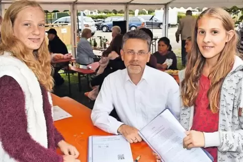 Haben Tombola-Lose verkauft: die Konfirmandinnen Emily Veith (links) und Hannah Sebök. Pfarrer Knut Trautwein quittiert es ihnen