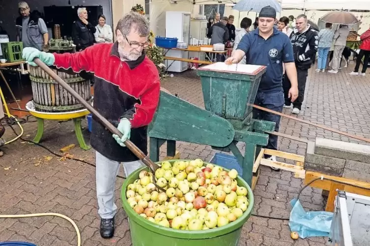 Berthold Neurohr (links) füllt die Äpfel in die Obstpresse. Adam Tolscik hilft ihm dabei.