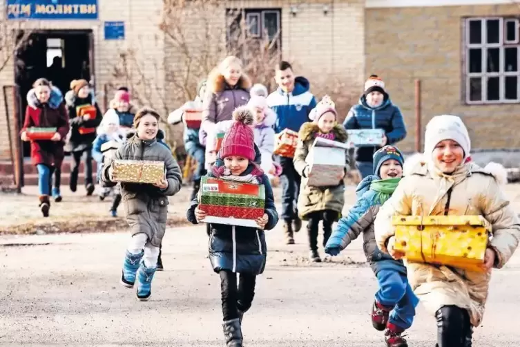 Nach der Schuhkarton-Verteilung in der Ukraine laufen die Jungen und Mädchen glücklich mit ihren Geschenkpäckchen nach Hause.