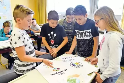 Schüler der Klasse 7a diskutieren über die beiden zur Wahl stehenden Logo-Varianten, in die Elemente von Schülerzeichnungen mit 