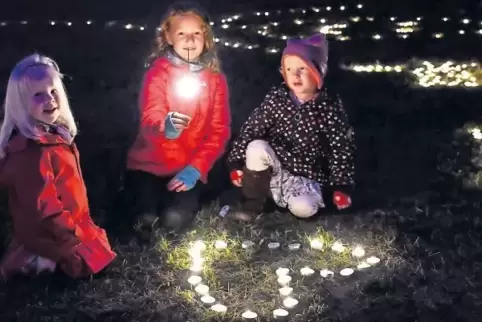 Leonie, Eva und Lotte (von links) haben ihre Teelichter in Herzform angeordnet.