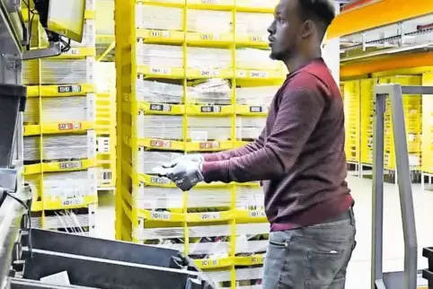 Hier wird der Versand vorbereitet: Transportroboter bringen mobile Warenregale heran. Shaib Jama Jusuf greift sich bestellte Art