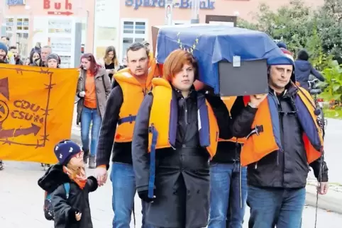 Der mit einer Europafahne bedeckte Sarg wird von den Demonstranten durch die Stadt getragen.