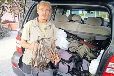 Willy Schuppert vor dem Auto eines festgenommenen Wilderers. In der Hand hält er Fallen, im Kofferraum liegt offen ein Gewehr.