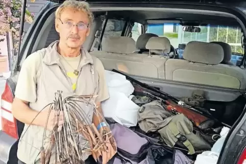 Willy Schuppert vor dem Auto eines festgenommenen Wilderers. In der Hand hält er Fallen, im Kofferraum liegt offen ein Gewehr.