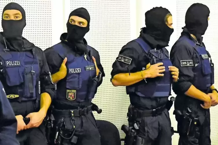 Die Verhandlung wird aus Sicherheitsgründen zeitweise von maskierten Polizeibeamten geschützt.