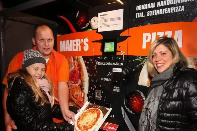 Vor dem Pizza-Automaten in der Schlichtstraße in Waldsee: Firmeninhaber Denis Maier mit seiner Frau Francesca und Tochter Giulia