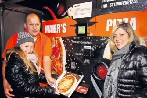 Vor dem Pizza-Automaten in der Schlichtstraße in Waldsee: Firmeninhaber Denis Maier mit seiner Frau Francesca und Tochter Giulia