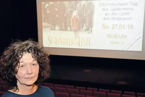 Die Hachenburger Kinobetreiberin Karin Leicher steht in einem ihrer Kinosäle, während auf der Leinwand die Vorschau für den Film