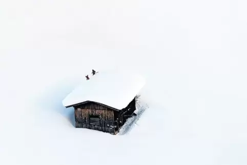 Österreich, Lofer: Menschen räumen Schnee vom Dach eines Hauses.