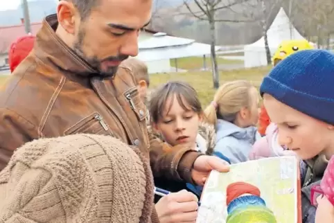 Martin Tielmann lässt sich auf am Gelände des VfB Reichenbach bei der Erstellung des Kinderortsplans von Grundschülern unterstüt