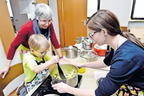 Der fünfjährige Linus versucht sich in Gerolsheim mithilfe seiner Mutter Stefanie Wahl (rechts) und Kochkursleiterin Marianne De