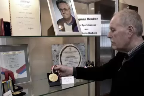 Ewald Marx setzt eine Goldmedaille des Behindertensportlers Siegmar Henkers in Szene. Marx ist Vorsitzender des Heimatpflegevere