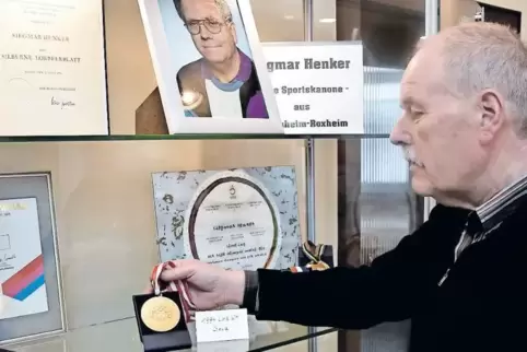 Ewald Marx setzt eine Goldmedaille des Behindertensportlers Siegmar Henker in Szene. Marx ist Vorsitzender des Heimatpflegeverei