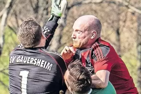 Michael Bechtold (rotes Trikot) vom TuS Ramsen gegen Torwart Patrick Schmitt und Jonas Steingass von der SpVgg Gauersheim.