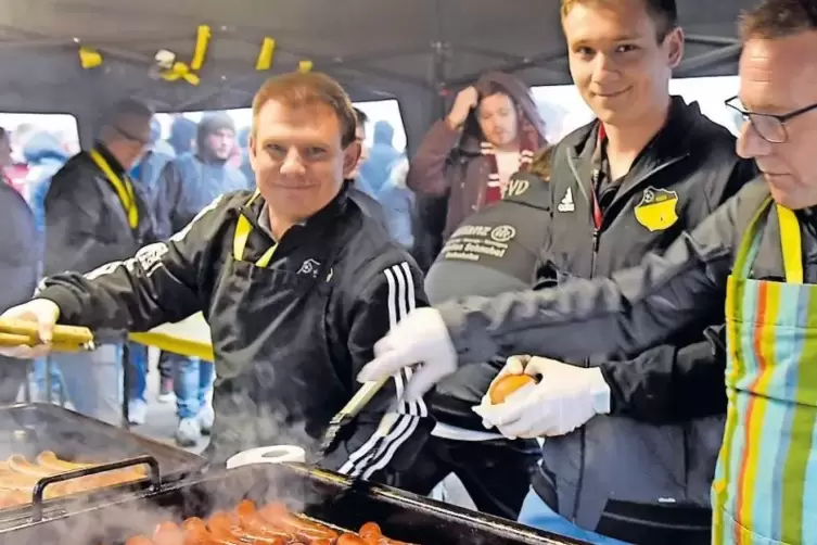 Mmmh, hei&szlig;e Typen: Rinds- (links) und Bratwurst brutzeln im Br&auml;ter. RHEINPFALZ-Mitarbeiter Timo Konrad (Mitte) wendet mit.