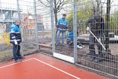 An den Ballzaun des Bolzplatzes schrauben die BASF-Gruppenleiter Bleche, damit der Sand vom Nachbargrundstück nicht auf den Bolz