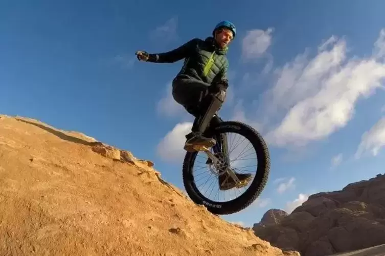 Auf dem Einrad jonglierend f&auml;hrt Lutz Eichholz auf seiner j&uuml;ngsten Tour in der jordanischen W&uuml;ste bergab.  Foto: David Weichenbe