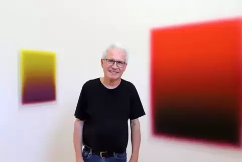 Galerist Tilo Ruppert mit den irisierenden Bildern von Thomas Deyle, die dieser „Lichtdeuter“ nennt.  Foto: Iversen