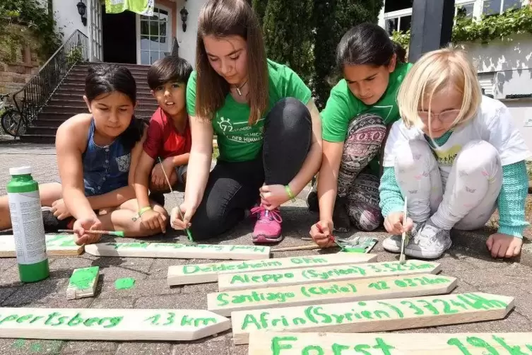 Hasna, Sobhi, Paula, Solin und Martha bauen einen Wegweiser auf dem die Entfernung zum jeweiligen Heimatort in KM angegeben ist.